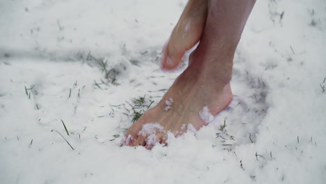 close-up of a caucasian male standing barefoot in the snow and enduring cold