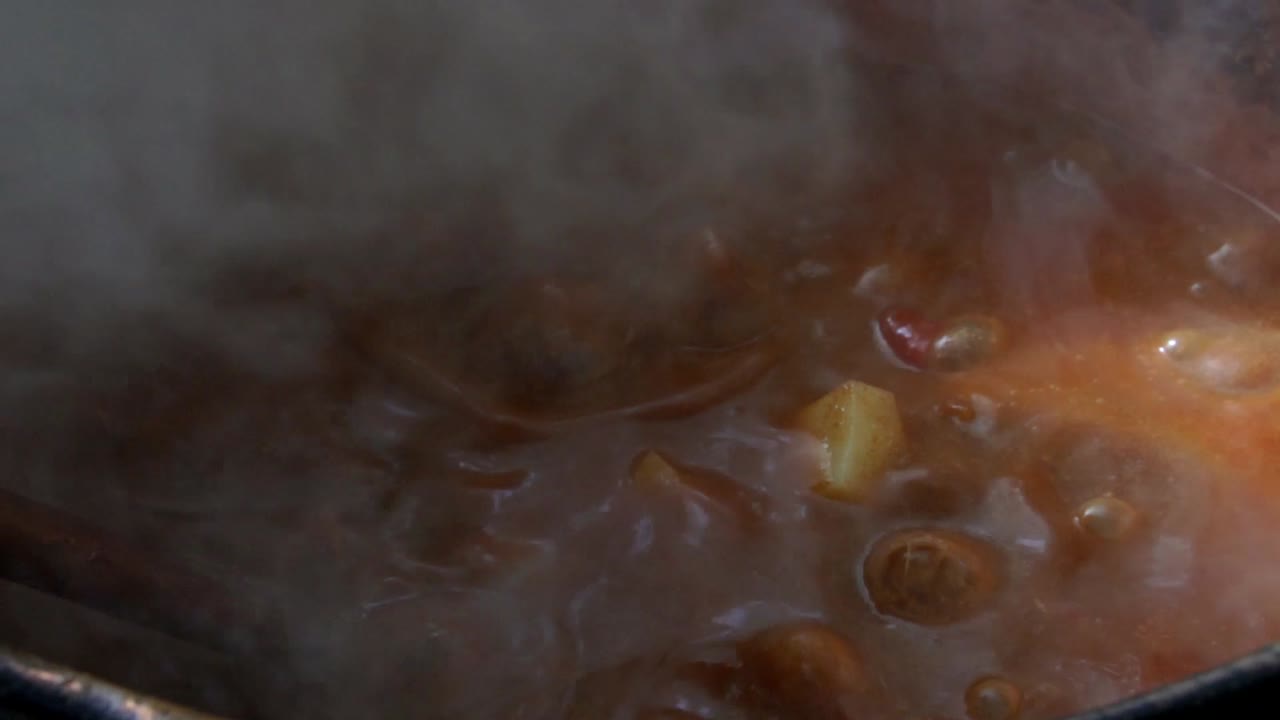 estofado de carne humeante burbujeando en una gran olla de cobre, cámara lenta