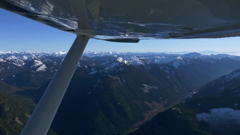 aerial airplane shot from cessna aircraft showing breathtaking mountain range with snowy peak during sunny day with clear sky