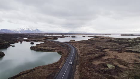 vista aérea de seguimiento de un automóvil que conduce cerca del lago myvatn en un hermoso paisaje en islandia