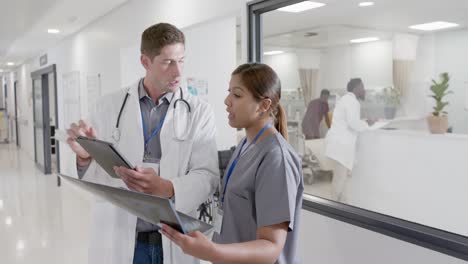 Busy-diverse-male-doctor-and-female-nurse-with-xray-and-tablet,-talking-in-slow-motion,-unaltered