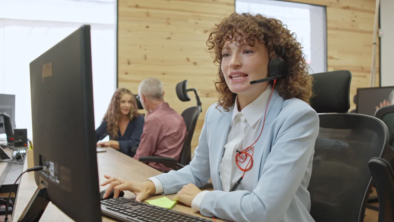 A customer service representative working at her desk in a busy office