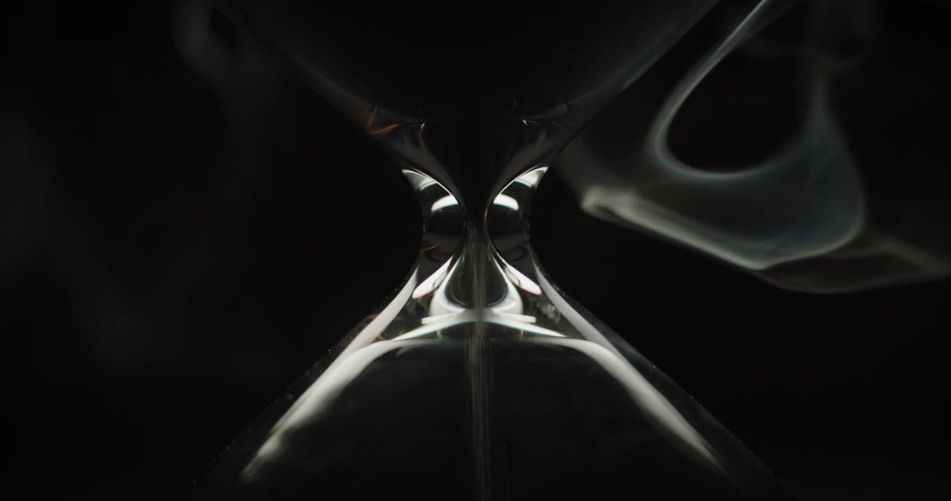 Sand pouring in hourglass with smoke