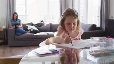 caucasian girl drawing in notebook in living room