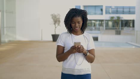 smiling woman using modern smartphone while strolling on street.