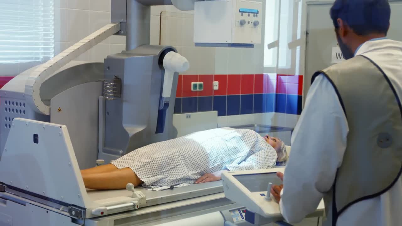 남성 의사 는 여성 환자 를  ⁇ 스레이 로 촬영 하기 위해 기계 를 설치 한다