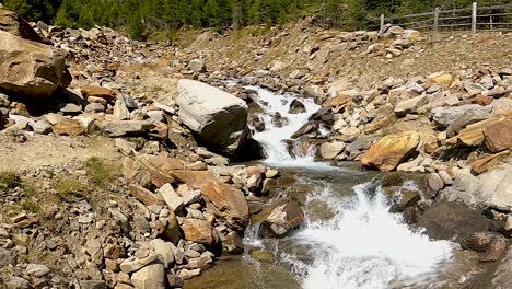 rapid flowing stream of mountains flowing downhill between red rocks in sunlight