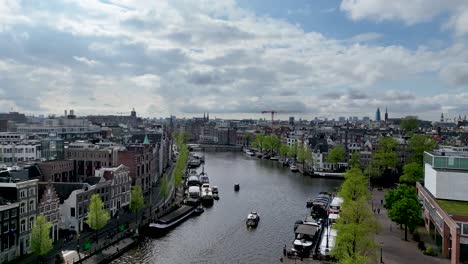 the drone is flying forward going up above the amstel canal in the city centre of amsterdam the netherlands aerial footage 4k