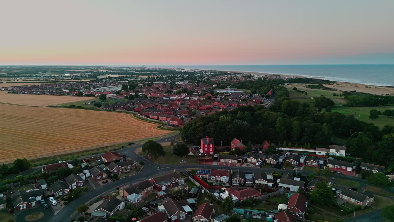 Sunset aerial footage of the coastal town and golf course in Skegness showing the town of Ingoldmells in the distance, with fairground rides