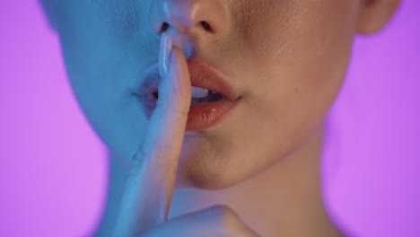 cámara lenta de cerca de los labios de una hermosa mujer llena mientras la joven aplica brillo labial a sus labios para prepararse para la noche con contraste azul naranja en su cara
