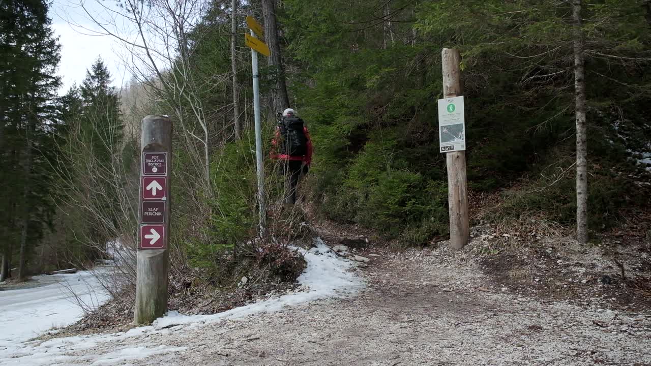 배낭을 메고 빨간 점퍼를 들고 폭포를 향해 하이킹 코스를 걷는 남자
