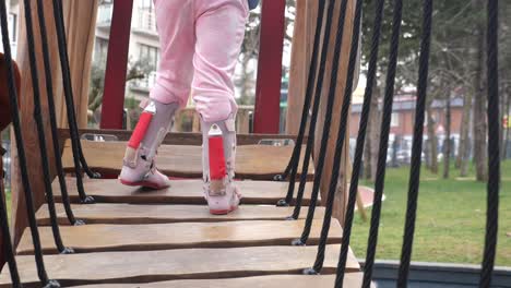 a young girl walks on a wooden bridge in a playground