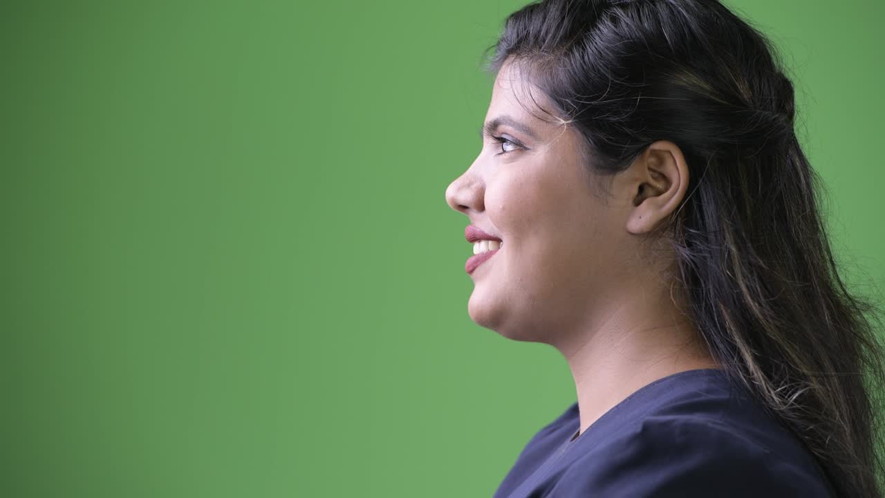 Young overweight beautiful Indian businesswoman against green background