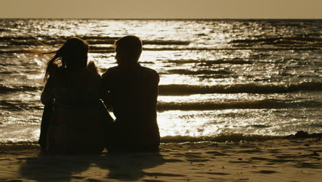 Siluetas-De-Parejas-De-Enamorados-Sentados-En-Un-Fondo-Del-Mar-Que-Refleja-La-Atardecer-Rea