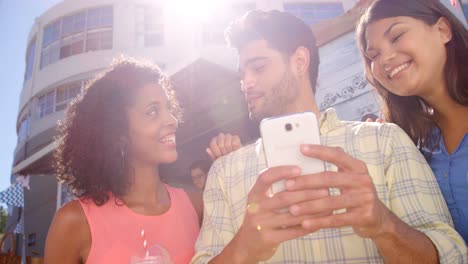 Friends-interacting-while-using-mobile-phone-at-counter