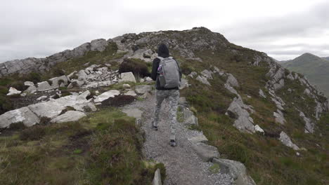 Slow-motion-Dolly-shot-of-a-Girl-walking,-hiking-in-Connemara-National-Park-on-the-trail-on-top-of-a-diamond-hill-in-Ireland-4K