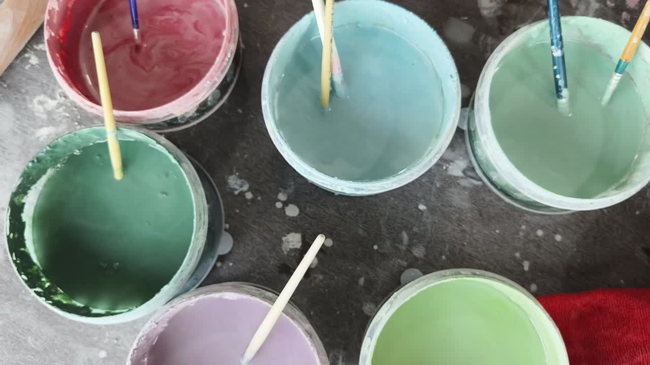 Bovenaanzicht van kleurrijke verf en penselen in een kunststudio