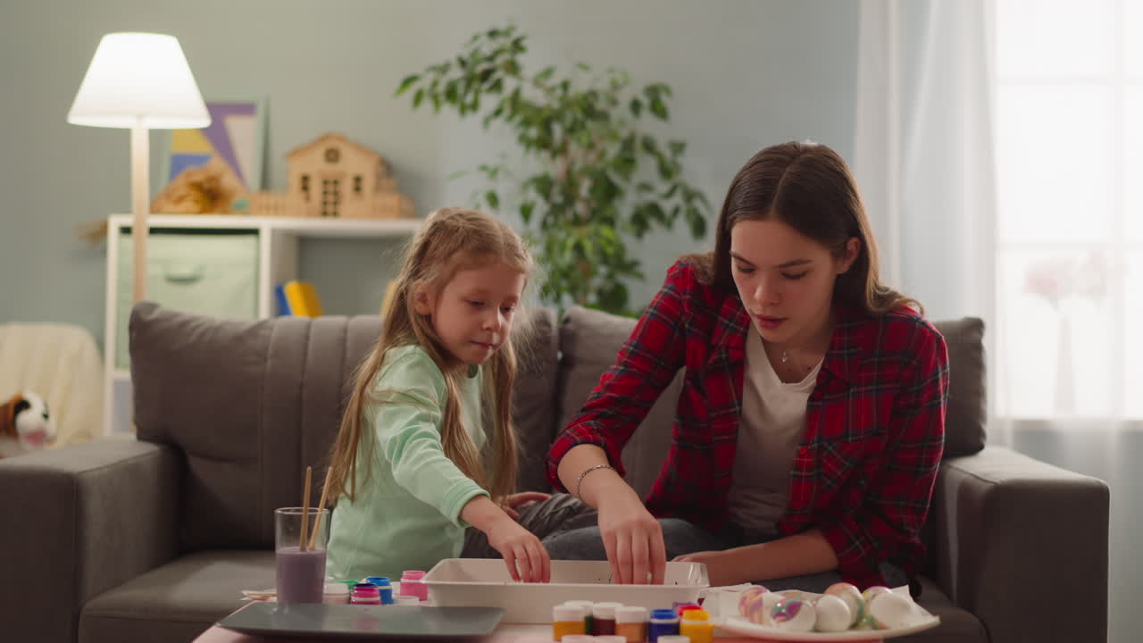 adolescentes y niñas pequeñas colorean huevos hervidos para la fiesta de pascua