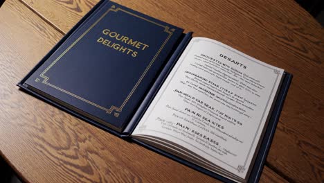 a top-down video shot of an elegant menu on a wooden table, showcasing a classic design with gold