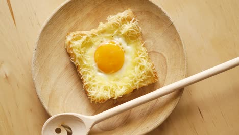 top view of toast with fried egg and cheese on wooden kitchen table