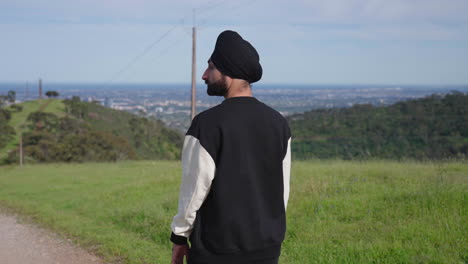 portrait of a punjabi sikh man walking downhill with dense mountains in the background