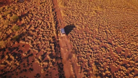 aerial drone bird eye top following 4wd truck down gravel road in australian desert after bushfire