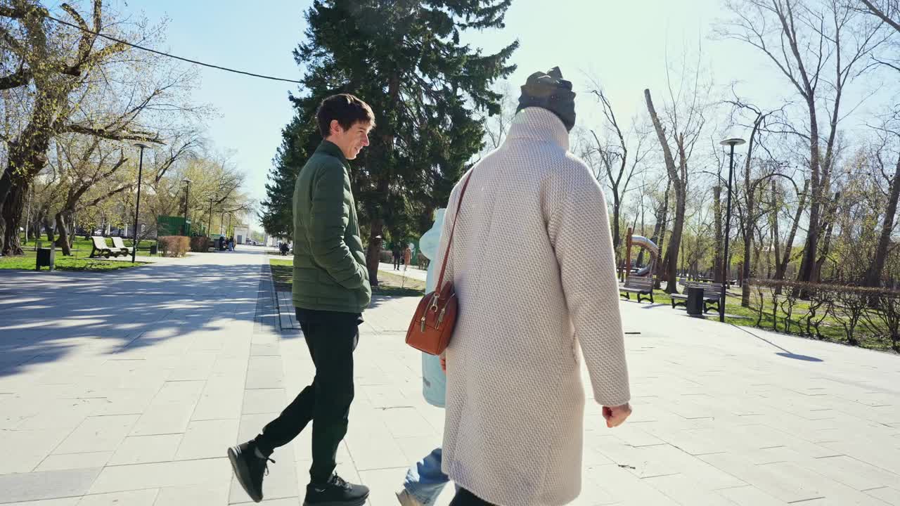 Three People Walking and Talking in a Sunny City Park