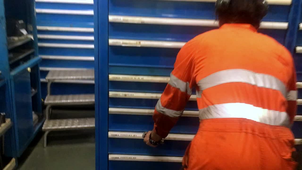 paseo del ingeniero para recoger la extracción de tuercas y tornillos en la sala de piezas de repuesto