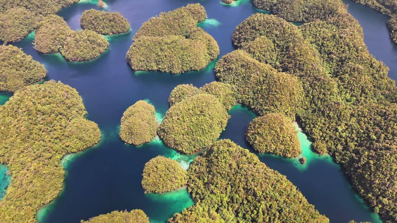 Aerial shot of Sohoton Cove, Siargao, features classic karst topography with densely forested limestone islets, tidal inlets, shallow lagoons, and vibrant blue water, part of Bucas Grande archipelago