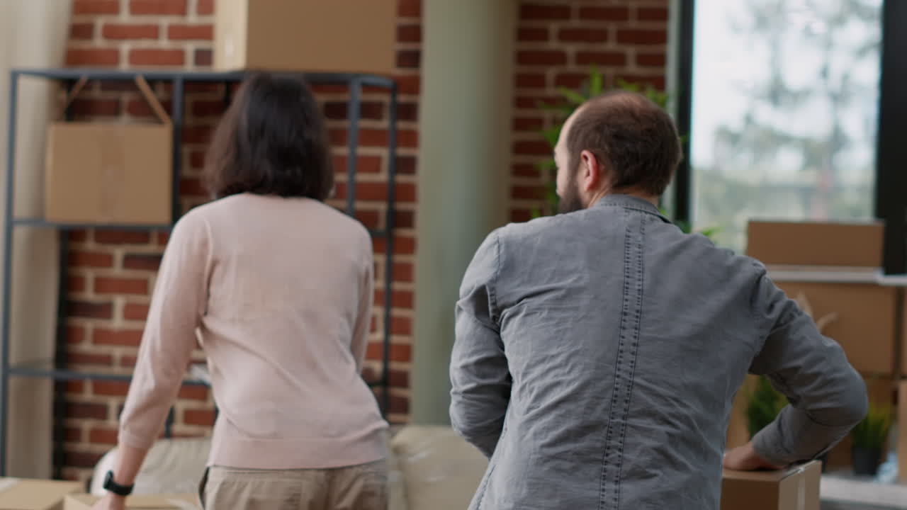 Married couple carrying carton boxes in apartment flat