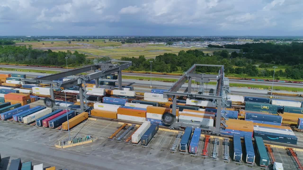 Aerial View of a Large Intermodal Shipping Container Yard with Trains and Cranes