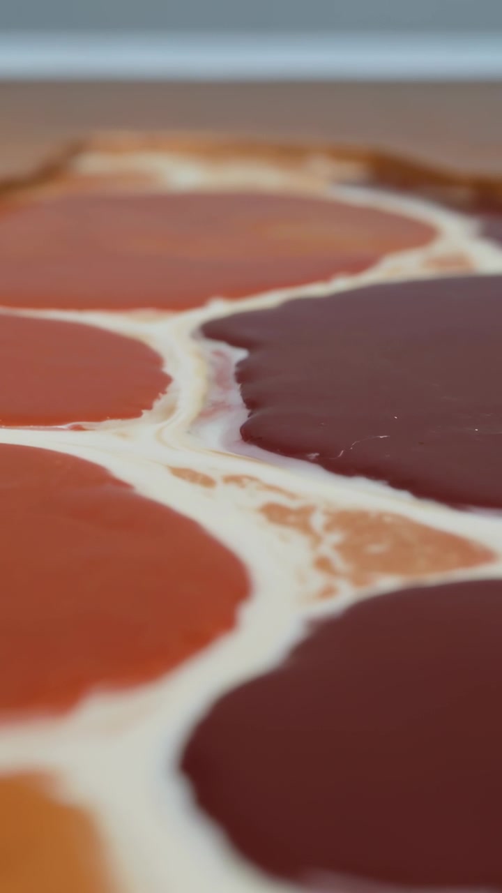 Vertical video: Shifting lens revealing pastry settling in kitchen to show tricolored glossy jams