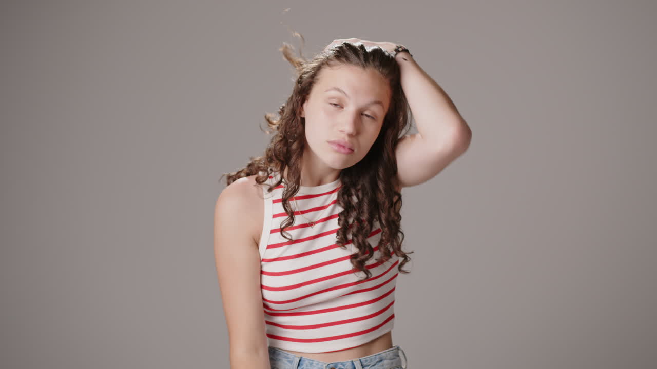 젊은 갈색은 카메라를 바라보고, 머리카락을 고치고 미소 짓고, 스튜디오 촬영