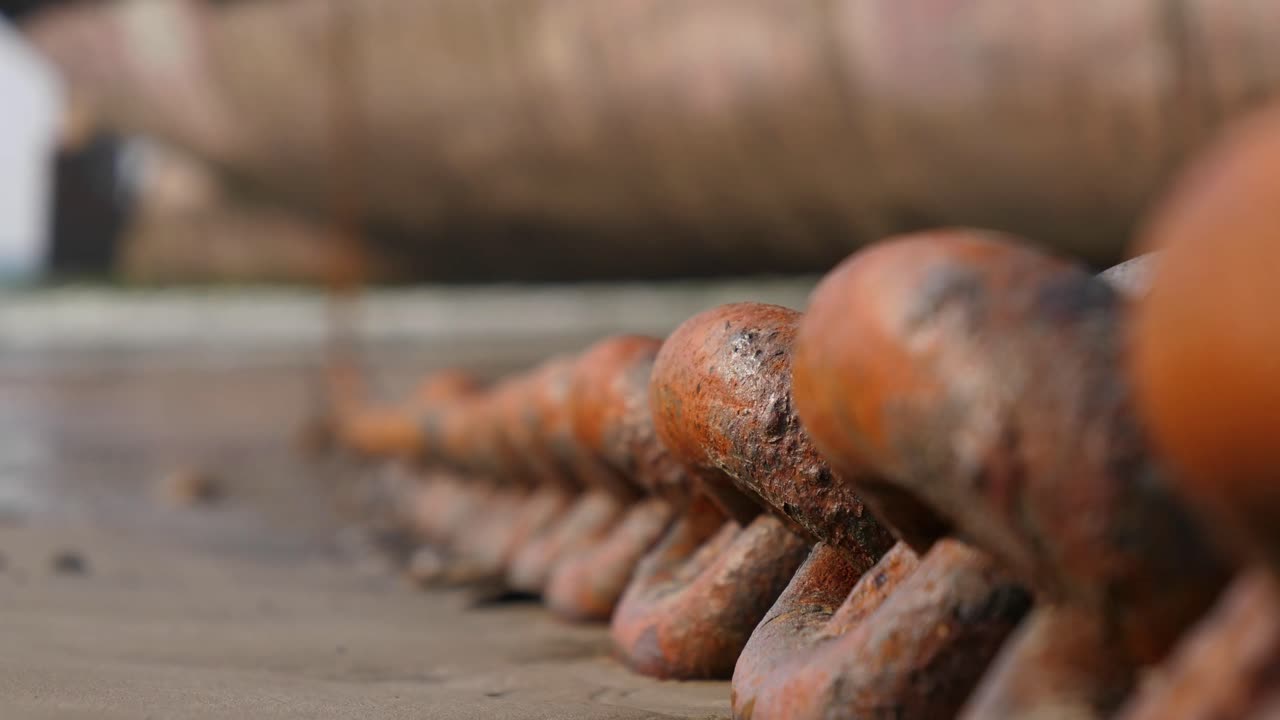 Rusty Anchor Chain Laid Out On Beach Connected To Ship