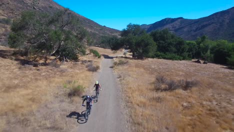 good aerial following two mountain bikers riding in the california mountains 1