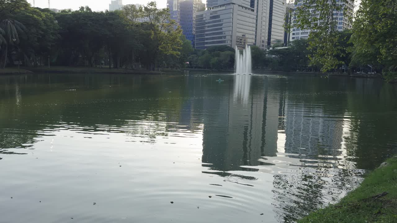 edificio moderno reflejo en el agua del lago en el parque lumpini bangkok tailandia