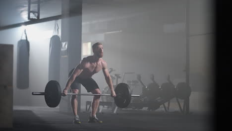 Slow-motion:-Brutal-athlete-lifts-the-bar-above-himself-performing-a-jerk-a-spinning-push.-A-man-is-engaged-in-weightlifting-on-a-dark-background-portrait.-Concept-strength-power-playing-sports.