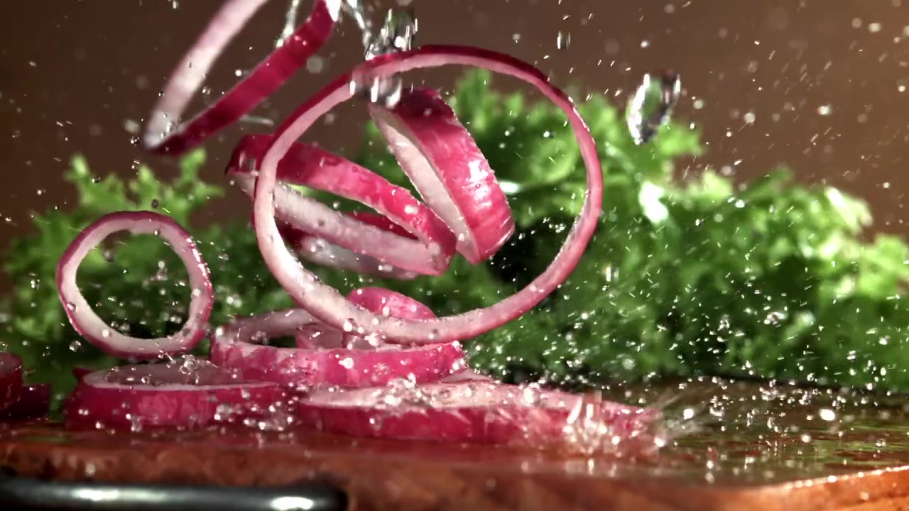 Slow Motion of Red Onion Rings Splashing Water on Cutting Board