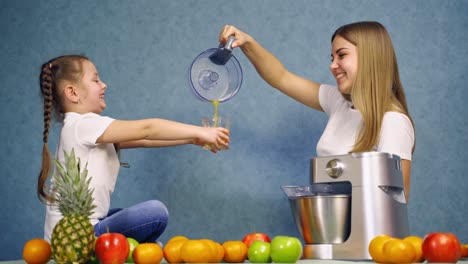 happy family drinking juice. smiling girl sitting on the table with fruits and juice
