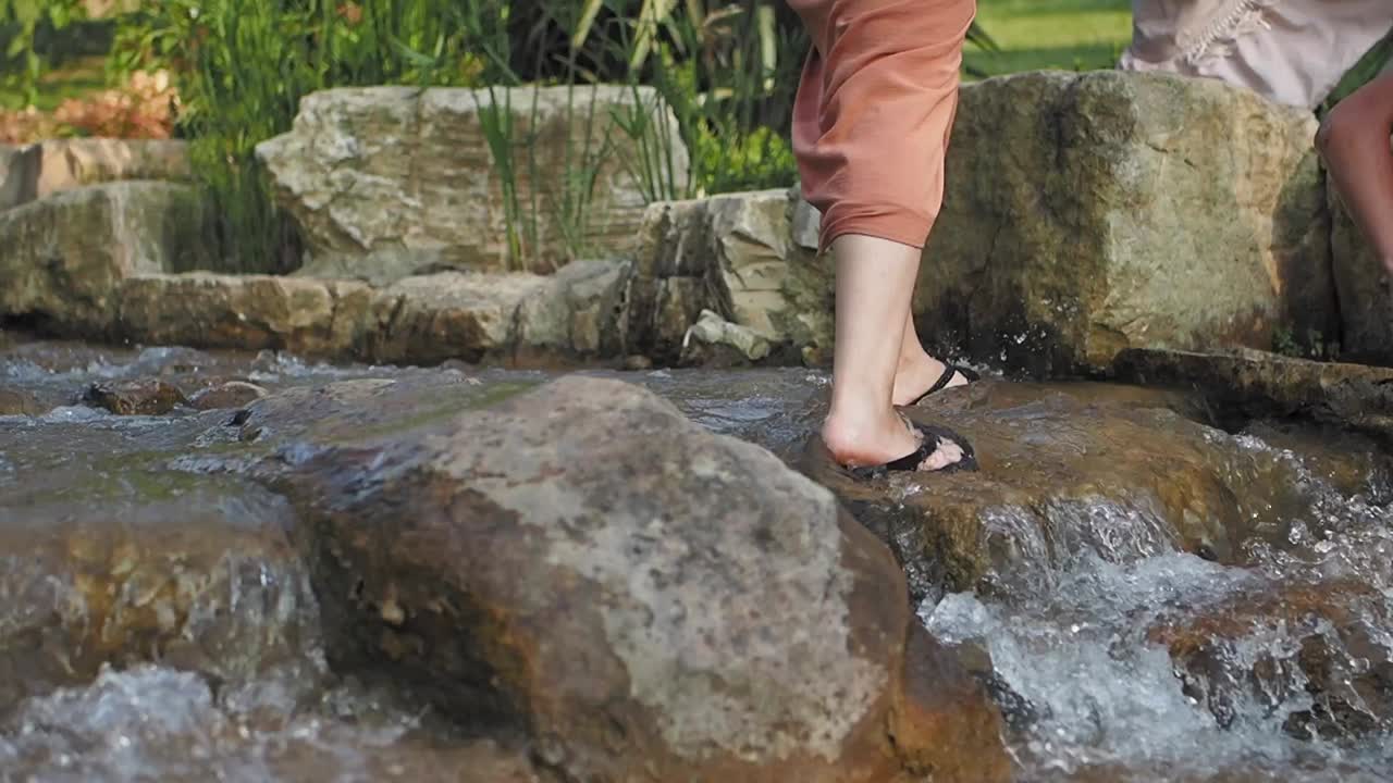 Woman walking through a stream in sandals