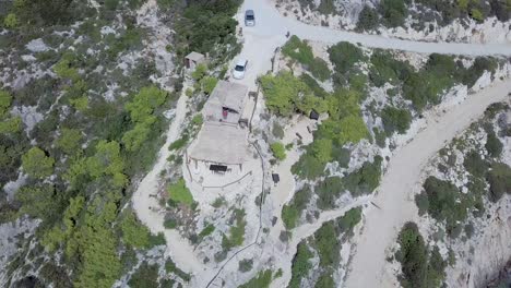 Inward-rotating-drone-footage-of-Korakonissi-Inlet-featuring-a-variety-or-cliffs,-rock-formations,-shoreline-and-a-small-Tavern