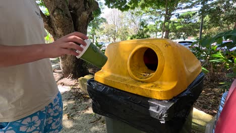 person disposing of a cup in a bin