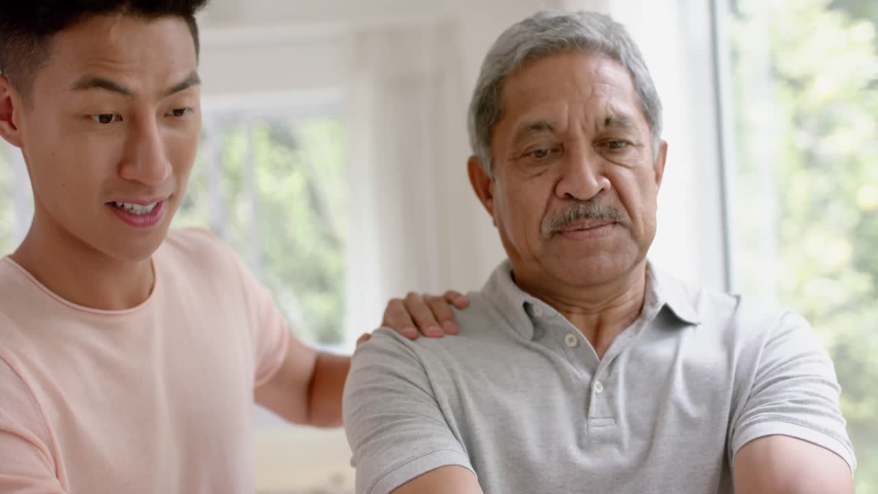 다양한 남성 물리치료사가 조언하고 단호한 고령자가 덤벨을 사용하여 느린 동작으로