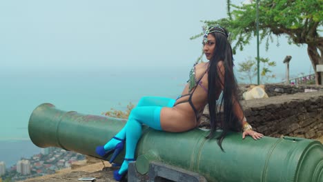 a radiant young woman sits gracefully on a cannon at a coastal fort