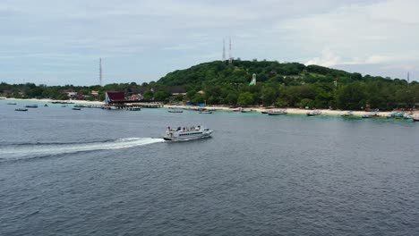 large-white-ferry-boat-approaching-Gili-Trawangan-Island-on-overcast-day-in-Indonesia,-aerial