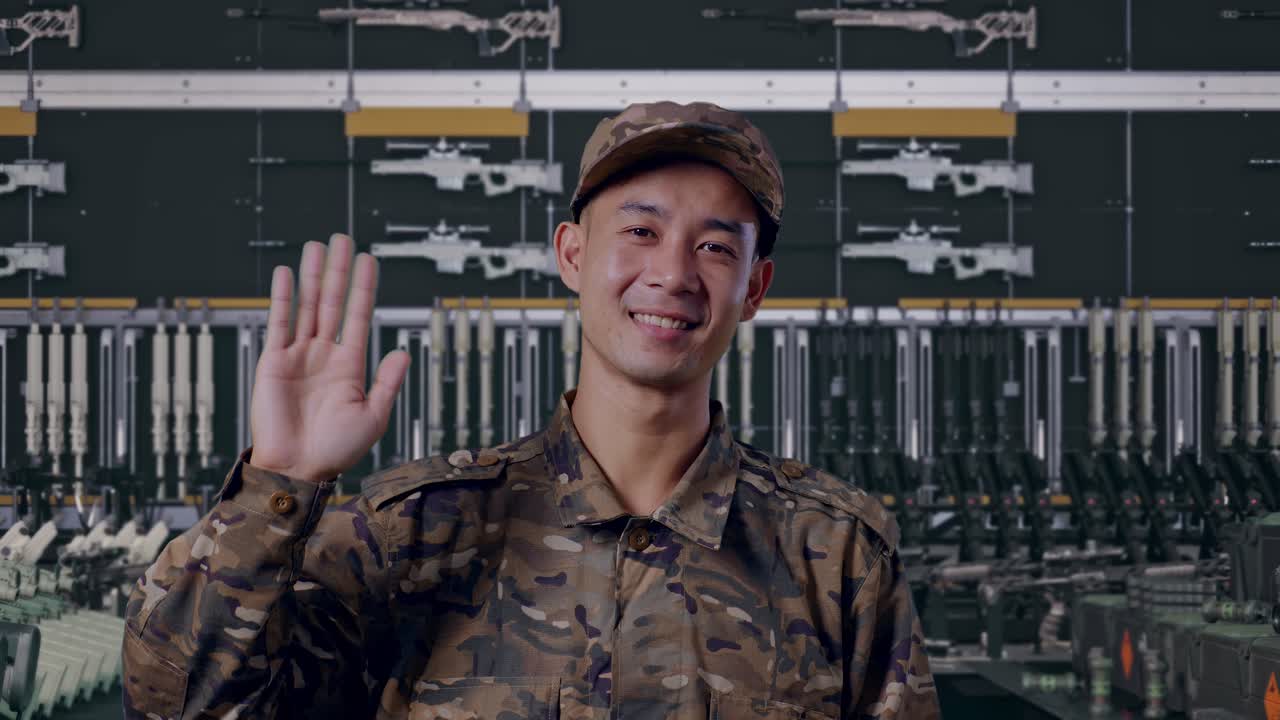 primo piano di un militare asiatico che sorride, saluta con la mano e dice ciao in un arsenale militare