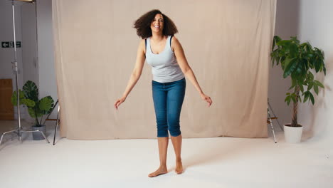 studio portrait shot of casually dressed body positive woman jumping in the air