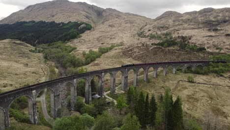 aerial shot of jacobite steam train at glenfinnan viaduct in scotland