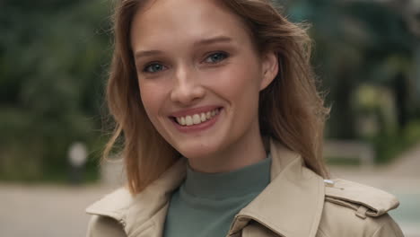 caucasian woman looking at the camera and smiling outdoors.