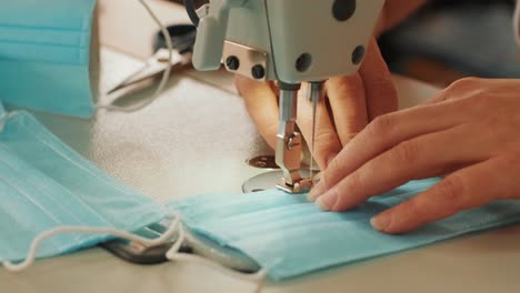 manos de mujer usando la máquina de coser para coser la máscara médica facial durante la pandemia de coronavirus. máscara de protección diy casera contra el virus.